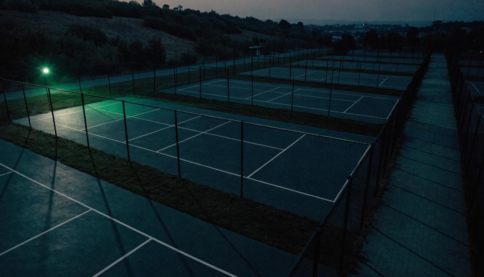 Wide view of an outdoor pickleball court complex with fresh line paint and a clear sky. Representative lifestyle image.